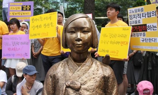 7月2日，在韩国首尔的日本驻韩国大使馆前，民众在慰安妇少女像旁手持标语参加抗议活动。