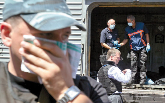 欧安组织调查专家站在装有遇难者遗体的冷藏车厢外