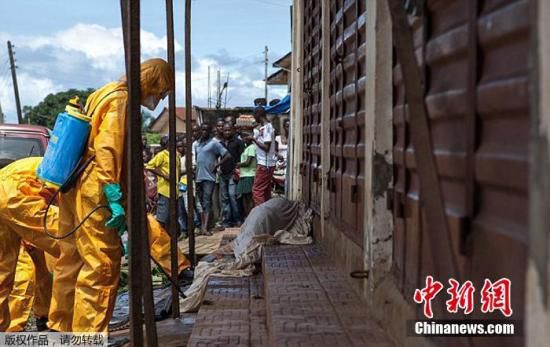 资料图：当地时间2014年10月8日，塞拉利昂弗里敦，卫生工作者正从街头一具疑似因感染埃博拉病毒而死