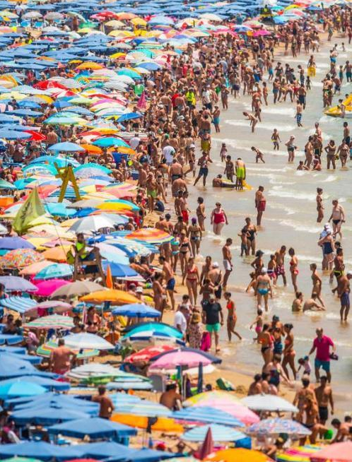 图为贝尼多尔姆海滩上，人头攒动，密集的游客堆满沙滩。