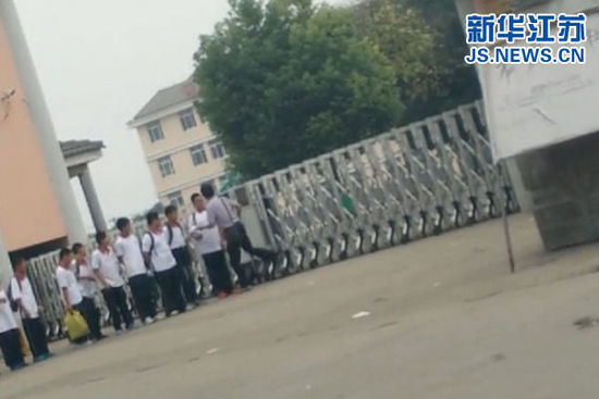 视频截图显示，一名男性工作人员正在抬脚准备踹学生。
