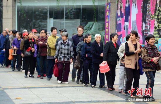 图为10月28日，在江西九江市一家羊绒皮草服装服饰博览会现场，老人们正在顶着寒风排队等待领取10元代金劵。