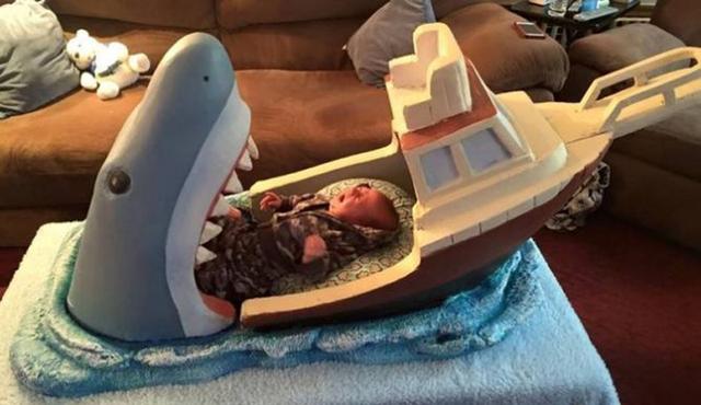 英国男子约瑟夫仿造电影《大白鲨》中的场景，为侄儿设计了一张“大白鲨吞小船”造型的婴儿床。（