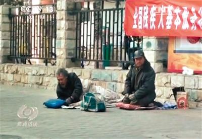 工人体育场北路，两位乞讨者路边乞讨，并轮流扮成“病人”（躺地者）。 央视截图