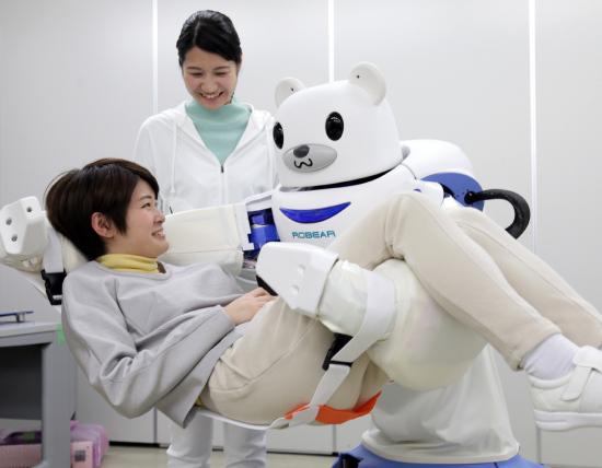 图为护理机器人演示将坐着的一名女性抱到沙发上。法新社。