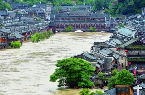 7月16日,沱江两边的商铺和远处的虹桥仍淹没在洪水中。 新华社发