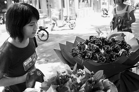 郑州市农业路一家花店摆放的玫瑰花吸引着一位过往女孩。