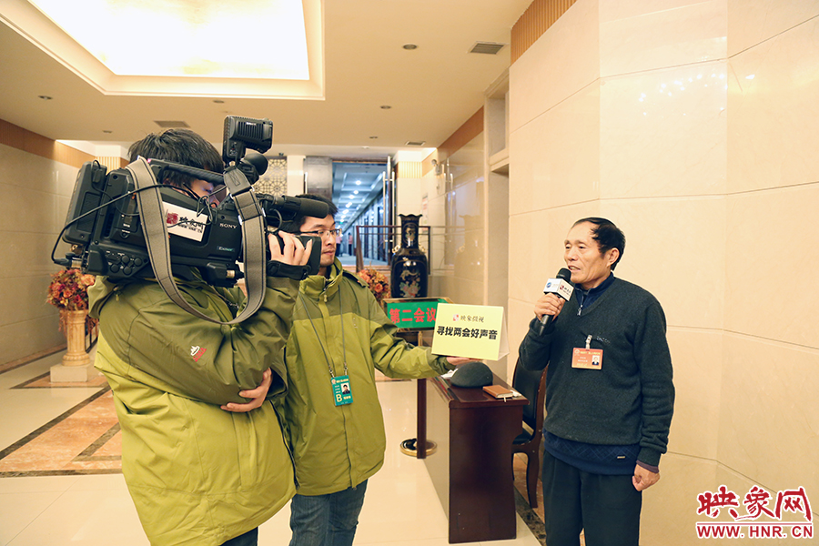 在采访人大代表李连成时，现场没有支架，大象融媒映象网记者梁文君深扛摄像机、胡向阳手举访谈展板。