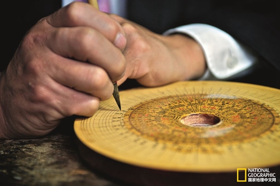 廖开祥在手工制作的罗盘上写字，40多岁的他已经做了26年的罗盘，是三僚村唯一做罗盘的人。